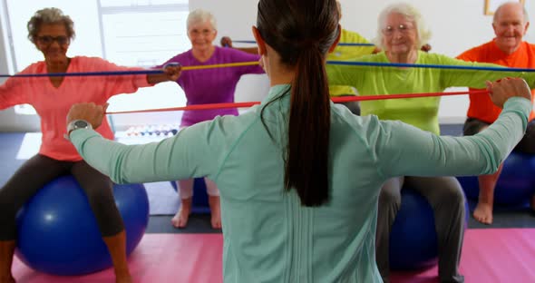 Rear view of female trainer training senior people in exercise at fitness studio 4k