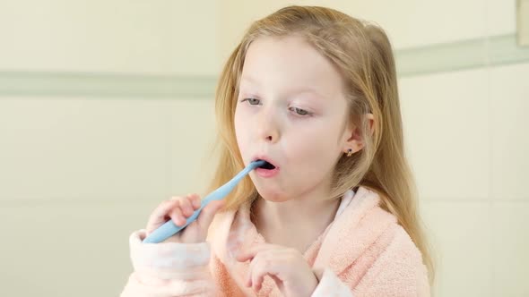 Happy Smiling Little Girl Brush Teeth Using Ultrasonic Electric Toothbrush in Bathroom at Home