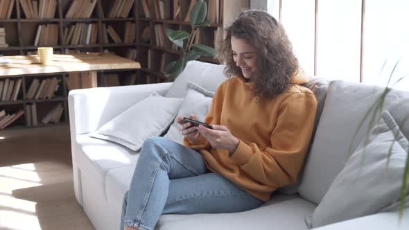 Happy Hispanic Girl at Home Watching Social Media Video Online Using Smartphone