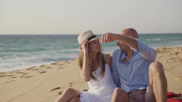 Couple Sitting on Plaid and Kissing on Beach