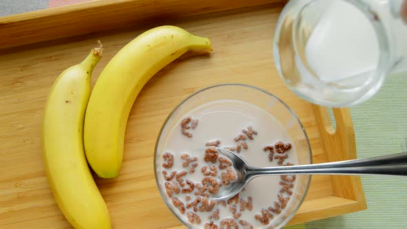 HD video, chocolate cornflakes in the form of an alphabet with milk in a bowl. Top view of a breakfa