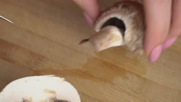 Woman Hands are Cut With a Knife Mushrooms on the Plank