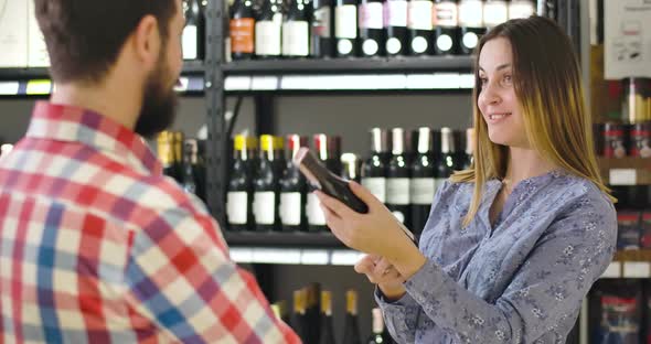 Portrait of Young Smiling Caucasian Woman Talking with Unrecognizable Salesman or Sommelier