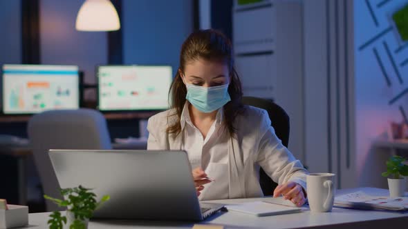 Employee with Protection Face Mask Working Late at Night in New Normal Office