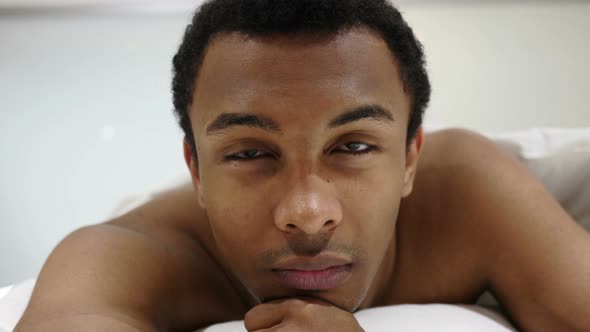 Serious African Man Lying on Stomach, Looking in Camera