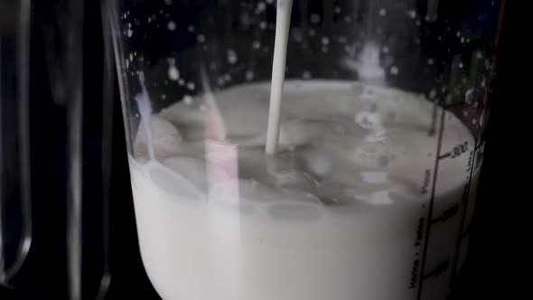 Close shot of pouring milk into a liter vessel with a big splash.