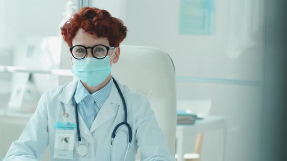 Portrait of Young Female Doctor in Mask at Desk in Clinic