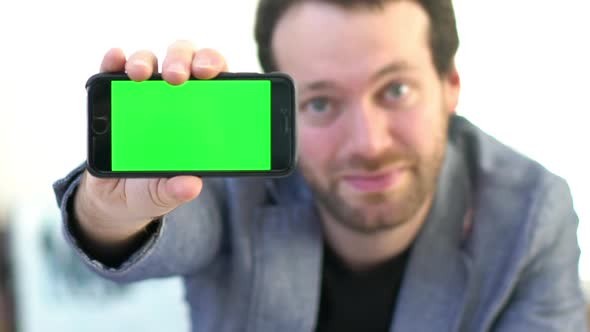 Cheerful man showing smartphone display to camera