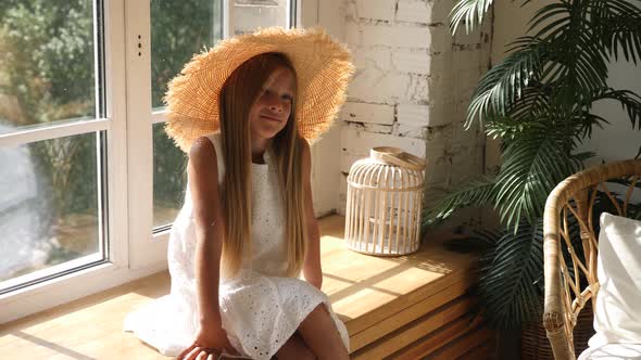 Girl in a Big Straw Hat and a White Dress Sitting