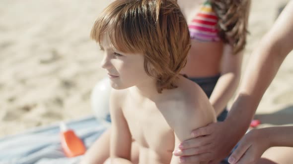 Slow Motion of Elder Sisters Hands Putting Sunblock on Boys Back