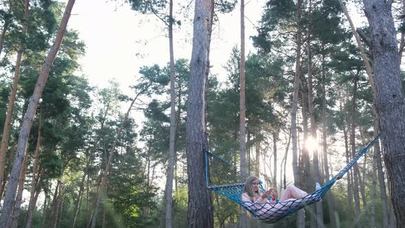 Woman Relaxing at the Forest on a Hammock