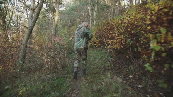 Back View of Soldier in Running with a Rifle in Forest and Looking Around