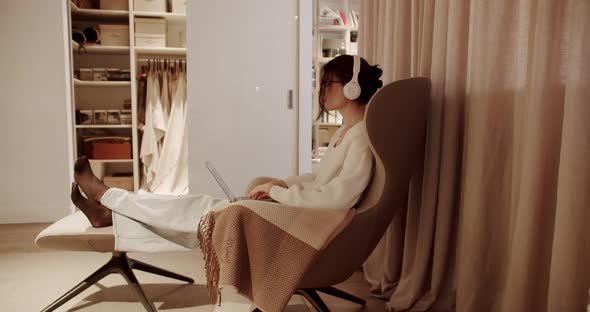 Beautiful Young Woman Works on Laptop Computer with Wireless Headphones