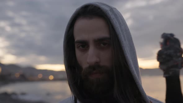 Hipster handsome man with long hair and beard holding flaming torch at the beach