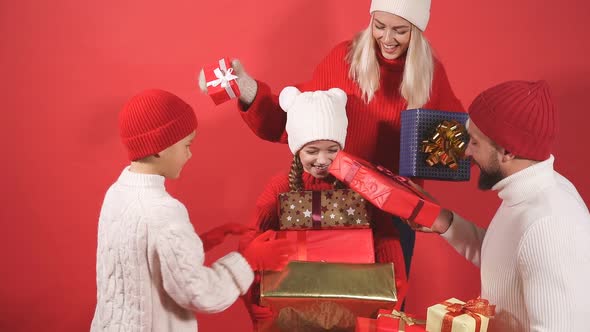 Happy Parents and Children in Winter Clothes Hold Gifts Presents in Hands Isolated on Red