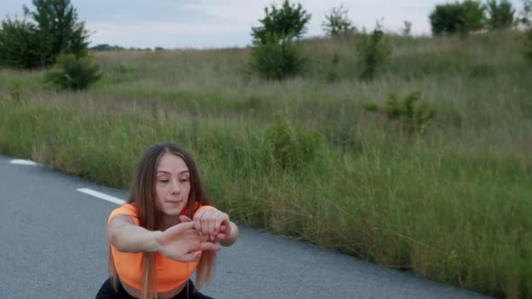 Beautiful Young Girl Doing Squats on the Road Among Nature at Sunset
