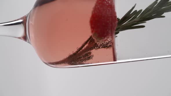 Vertical video, Close-up: a sprig of rosemary in a glass of bubbling champagne with strawberries