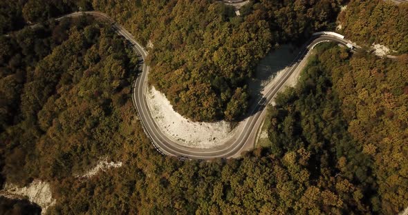 Aerial View of Car Driving Along The Winding Mountain Pass Road Through The Forest Trees. Autumn