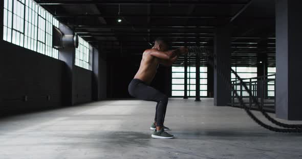 African american man exercising battling ropes in an empty urban building