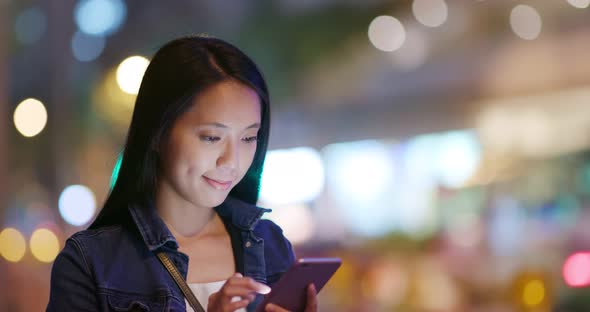 Woman use of smart phone in city at night