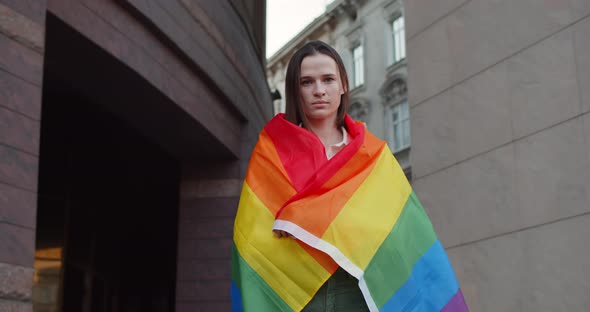 Portrait of Young Woman Covering Herself in Rainbow Flag While Looking To Camera. Millennial Good