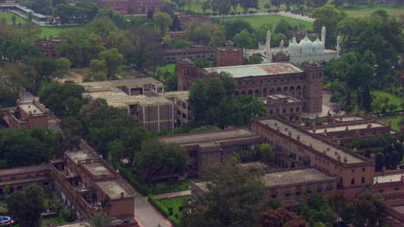 Aerial flight to the white beautiful Mosque over the old heritage buildings, Surrounded by Green tre