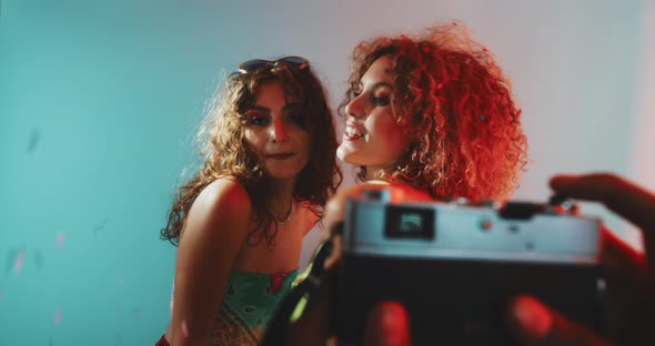 Two girls posing and dancing with confetti faling and neon light