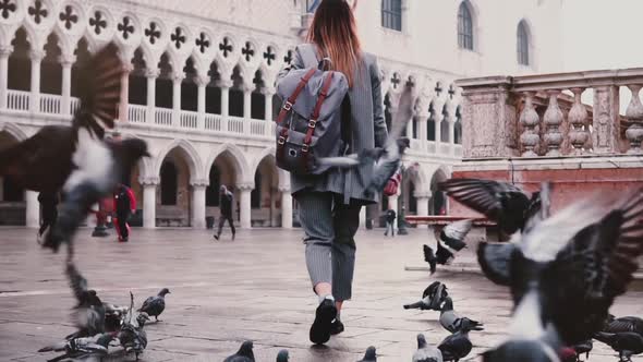 Big Flock of Pigeons Following Happy Female Tourist on Amazing San Marco City Square in Venice Italy