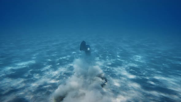 Boy Snorkels with Fins on the Seabed Raising Sand Smoke in the Ocean