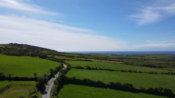 Vibrant green English countryside with sea in background. Aerial rising