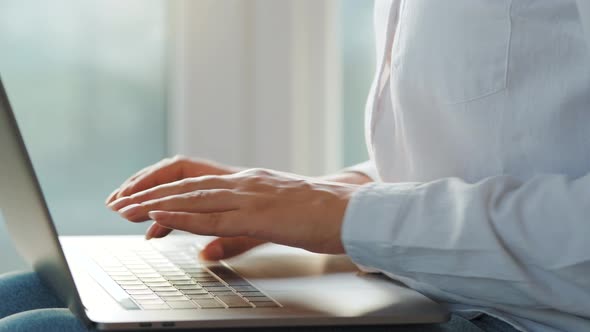 Woman Is Sitting on the Couch in a Cozy Room and Working on a Laptop