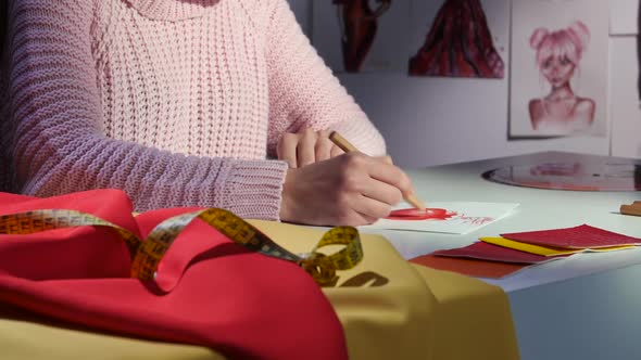 Designer's Hands Draw a Sketch of a Beautiful Red Dress. Close Up