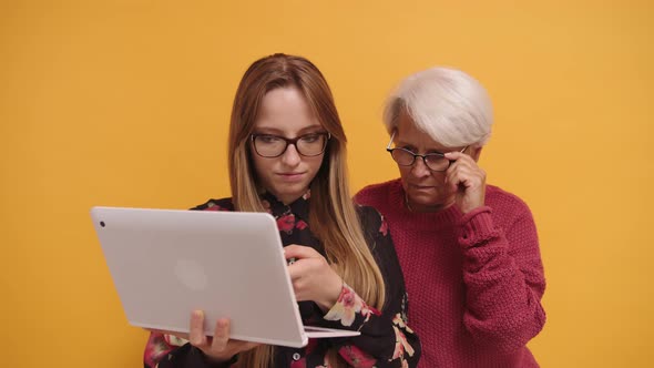 Young Woman Explaining To a Senior Lady How To Use Laptop. Slow Motion