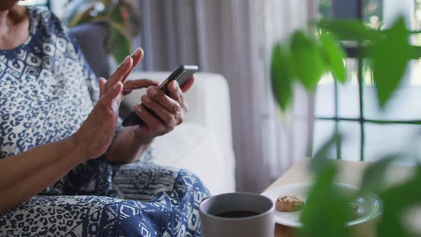 African american senior woman sitting on the couch and using smartphone