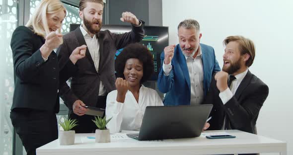 Businesspeople Getting Good News in Laptop Screen and Celebrating Victory with Raised Hands