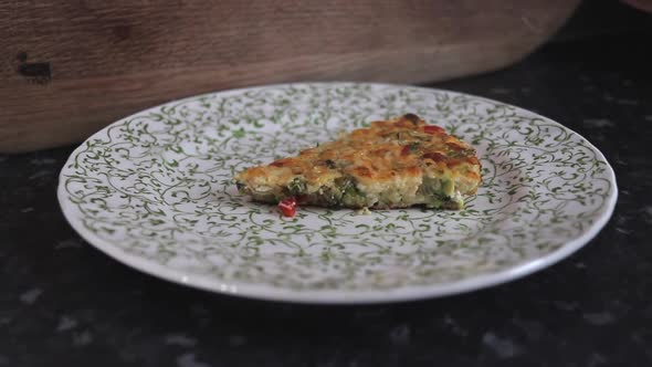 Tomato, red pepper, kale, zucchini/ courgette, onion and bacon frittata being placed on plate, slow