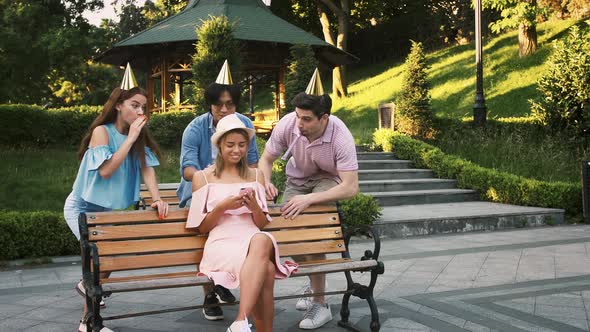 Young Birthday Woman Using Smartphone Sitting on Bench in Park