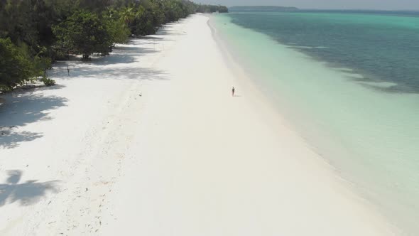 Aerial: Woman on white sand beach turquoise water tropical coastline caribbean sea