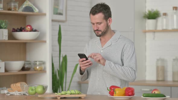 Young Man Using Smartphone While Standing in Kitchen