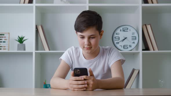 Portrait of a Boy of 13 Years Old Uses a Smartphone While Sitting at Home
