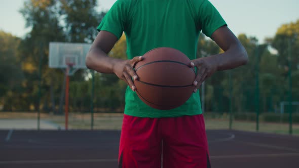 Basketball Player Holding Ball Outdoors at Sunrise