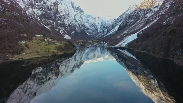 Spectacular flying towards Gudvangen in Unesco listed Naeroyfjord with mirror effect in glossy clear