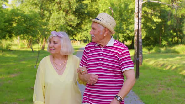 Senior Old Stylish Tourists Couple Grandmother Grandfather Having a Walk and Talking in Summer Park