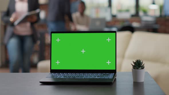 Laptop with Green Screen Display on Desk in Business Office