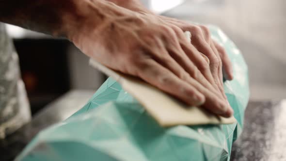 Close-up: a male artisan painter sculptor wipes the product, puts things in order in the workshop