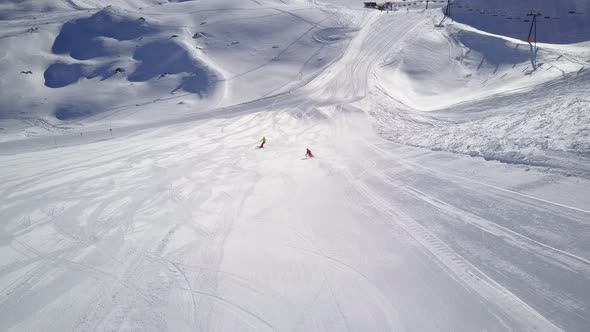 Aerial View Following Two Skiers in Skiing Area on Sunny Day