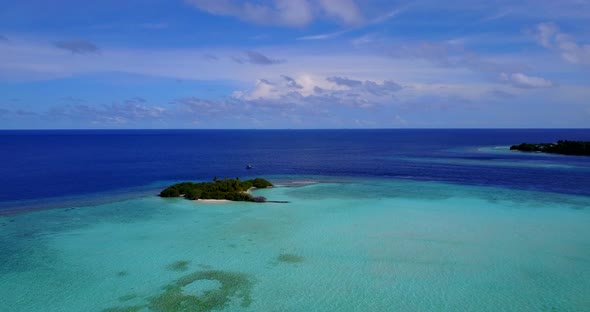 Luxury birds eye tourism shot of a paradise sunny white sand beach and blue ocean background in 4K