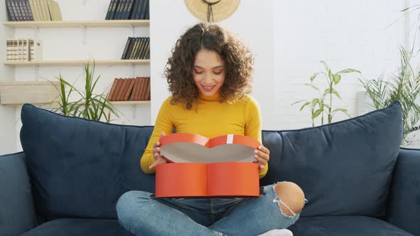 Attractive Woman Opens Red Gift Box in Form of Heart