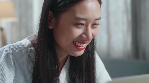 Close Up Of Asian Female Footwear Designer Smiling While Typing On A Laptop At Home