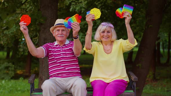 Stylish Senior Grandmother Grandfather Holding Squeezing Antistress Toy Simple Dimple Games in Park